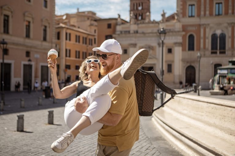 A small group of two mature tourist friends made up of a beautiful woman and a redhead man enjoying a sightseeing day in Rome, Italy