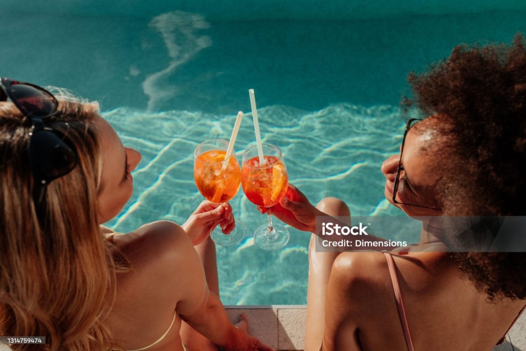 Female friends at a poolside summer party enjoying cocktails